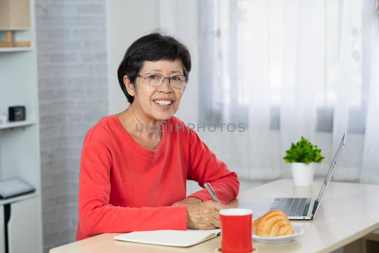 Senior asian woman relaxing using laptop computer while sitting on table.