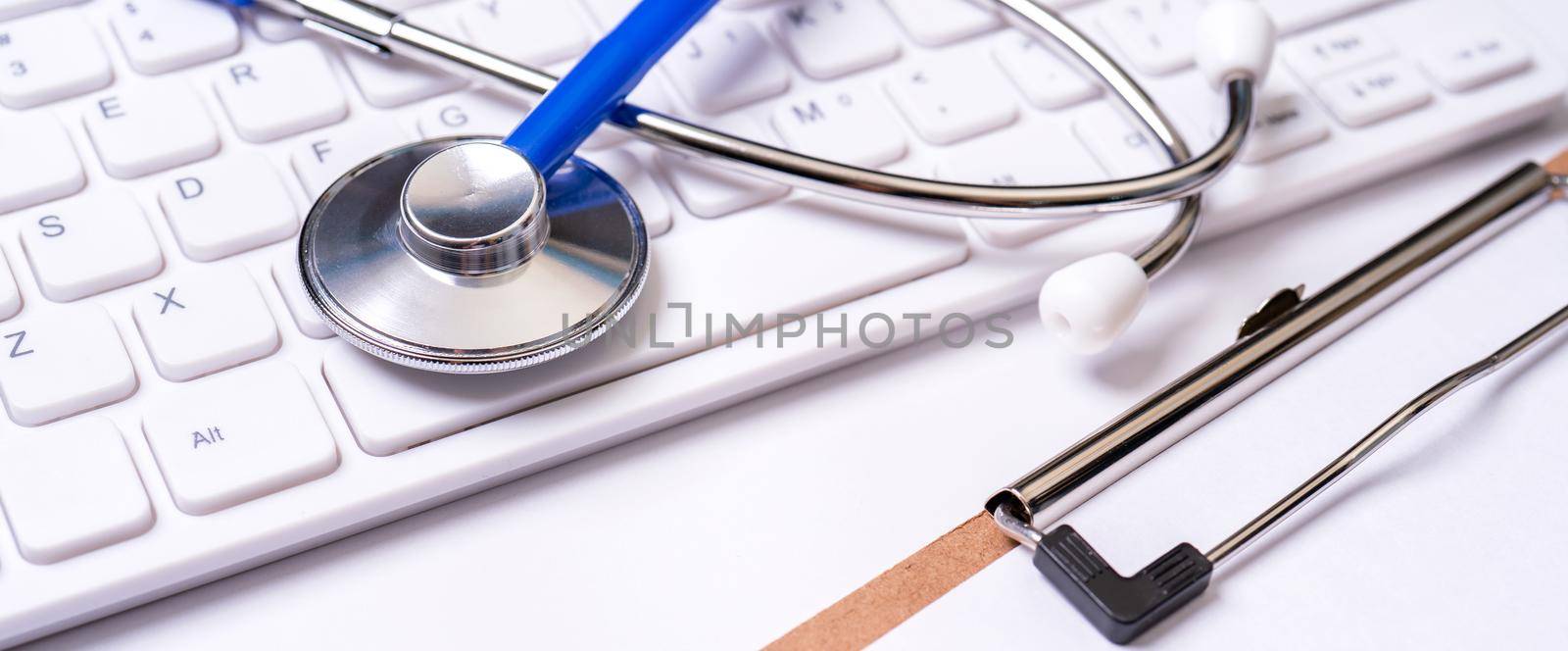 Stethoscope on computer keyboard on white background. Physician write medical case long term care treatment concept, close up, macro, copy space by ROMIXIMAGE