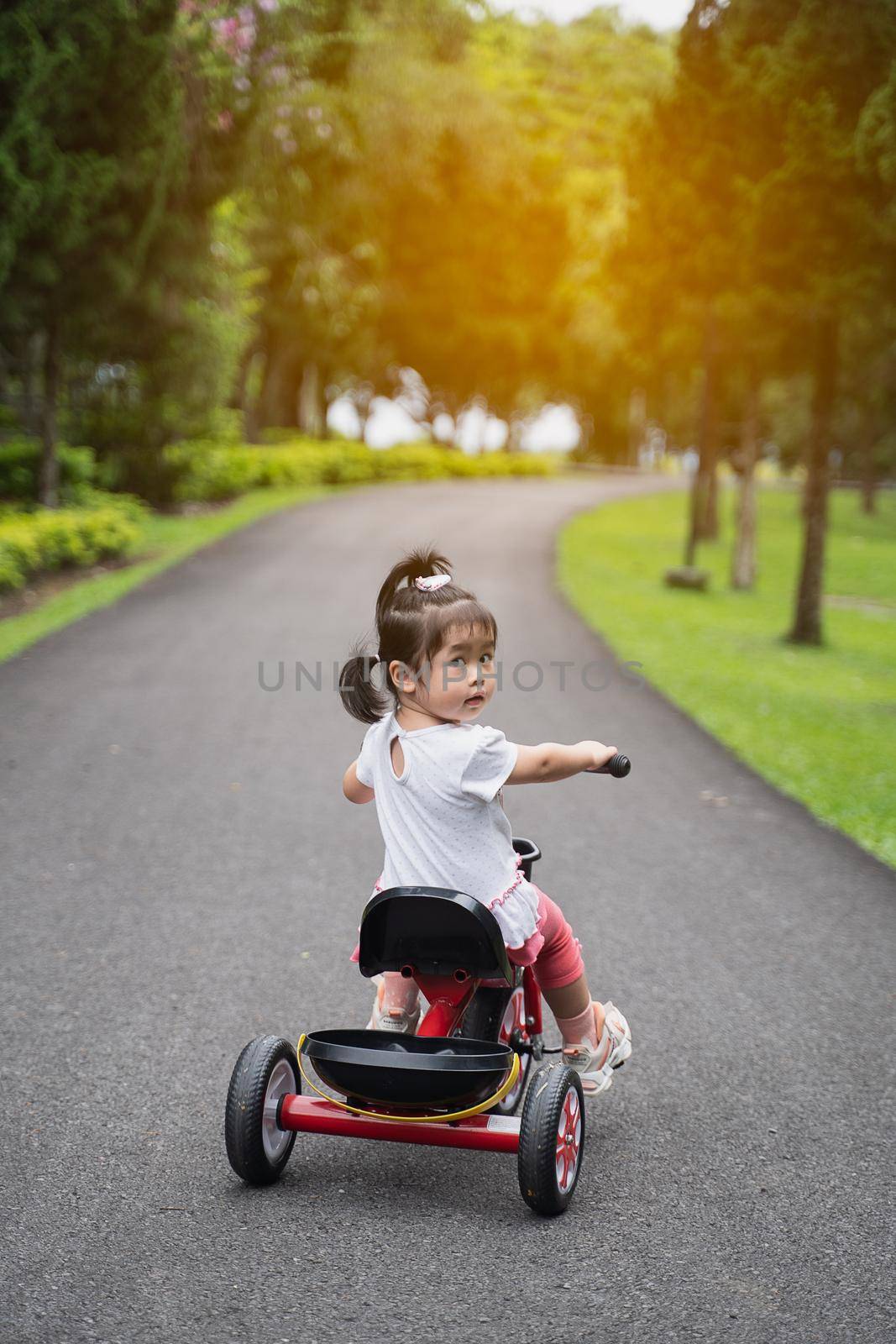 cute baby riding bicycle in the garden by Wmpix