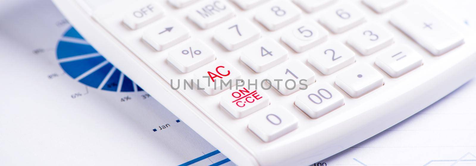 White calculator and report with chart and graph, concept of annual financial profit overview, banking and investment, close up, copy space, macro