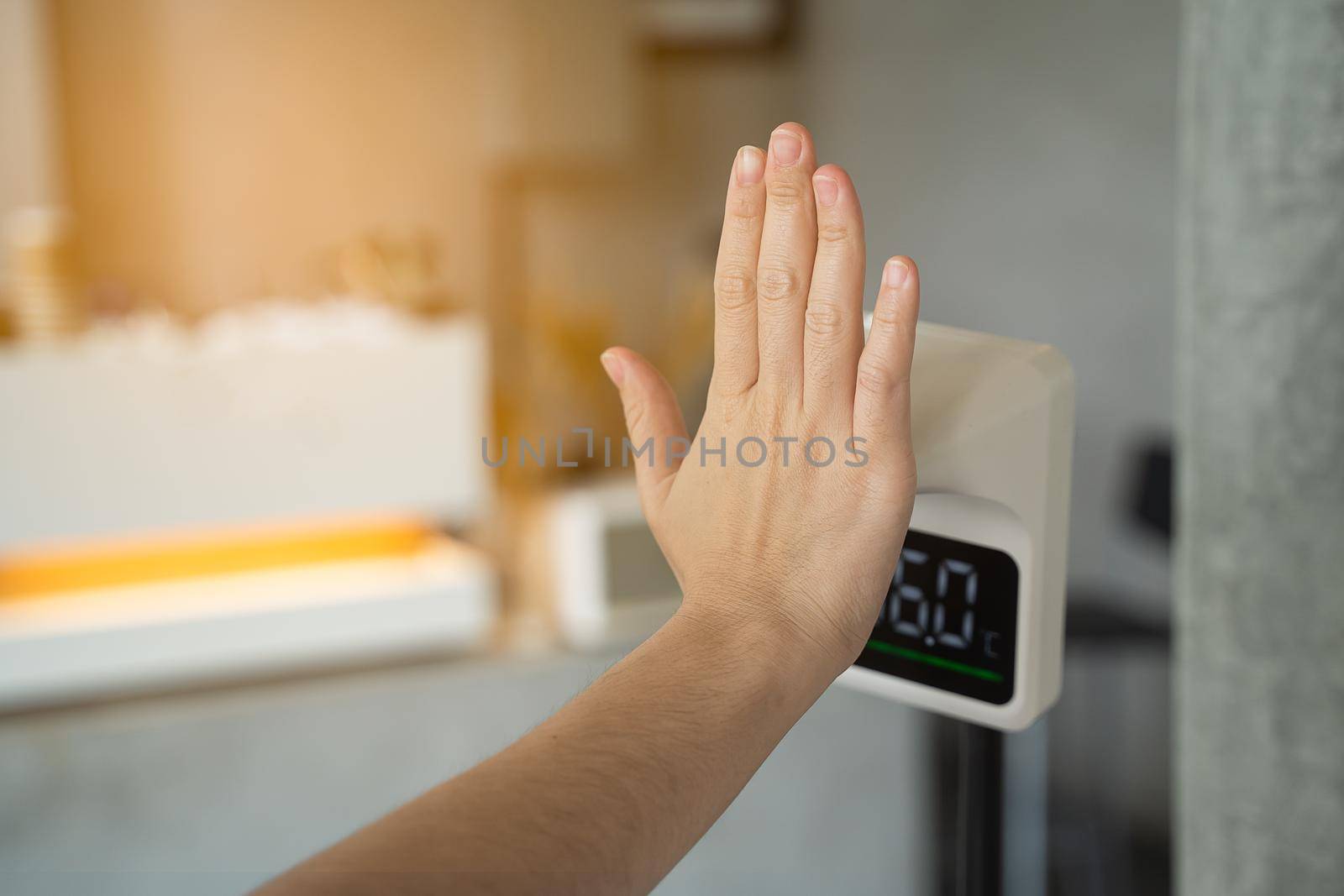 Women hand checking temperature before entering cafe with digital automatic body measuring temperature check machine