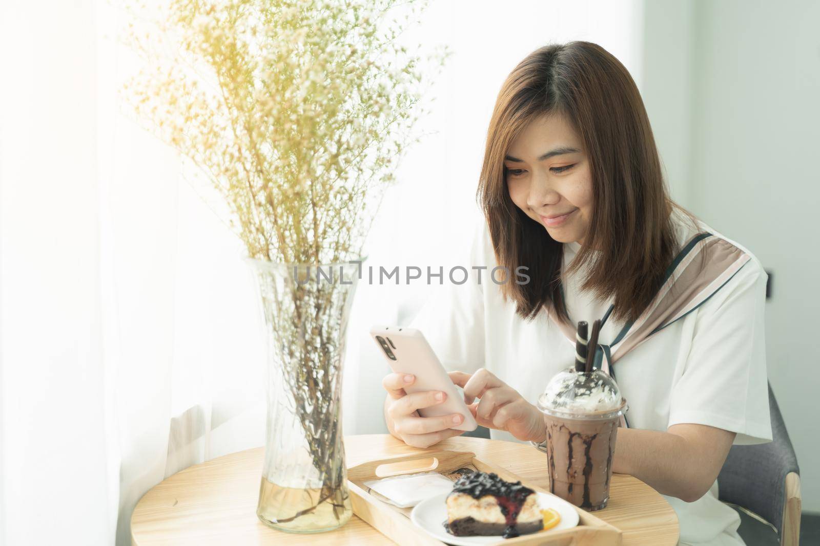 beautiful girl smiling using mobile phone in the cafe, girl eat coffee and cake by Wmpix