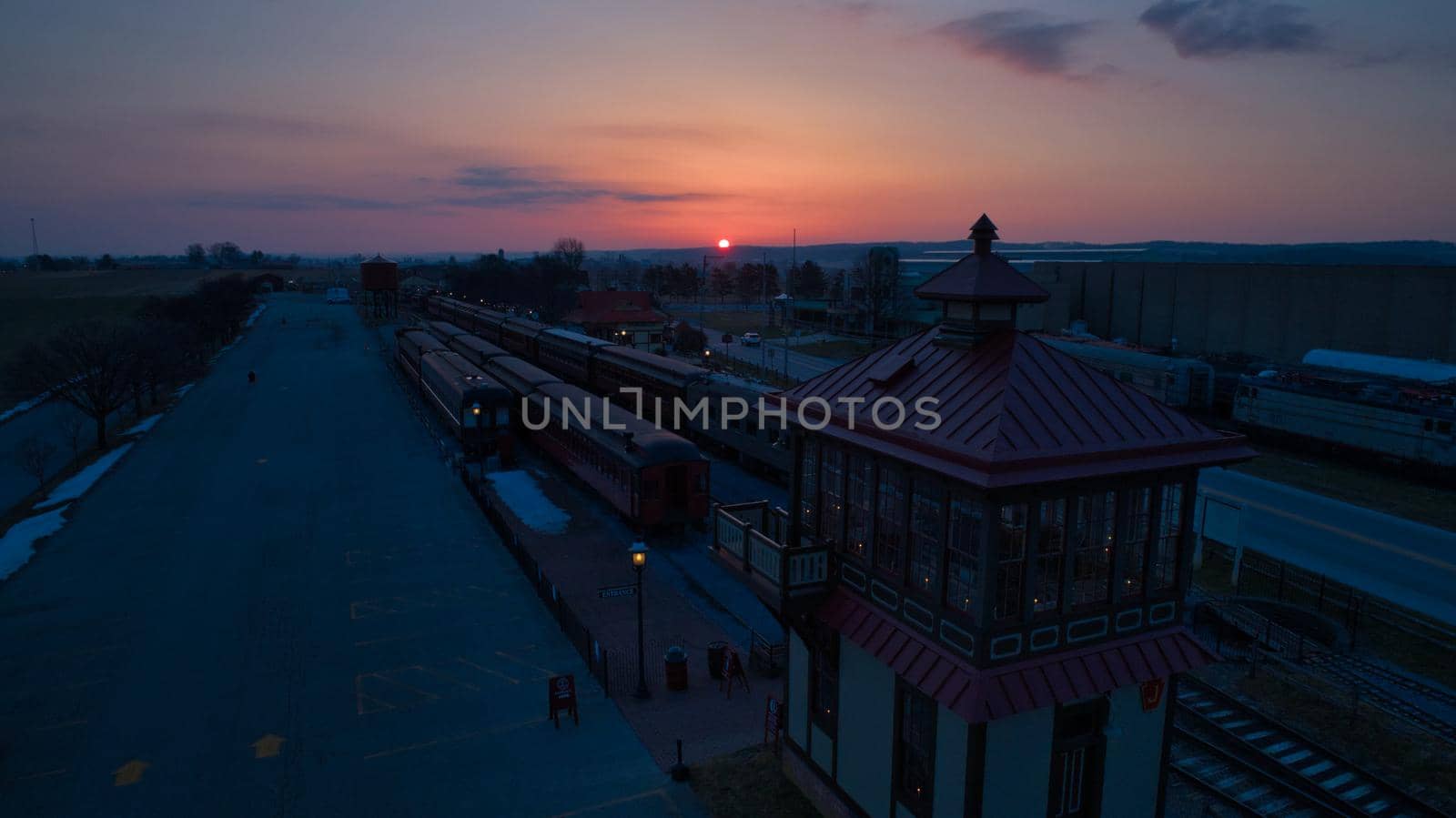Sunrise With Blue, Red Sky and Clouds Looking Over a Train Station and Yard