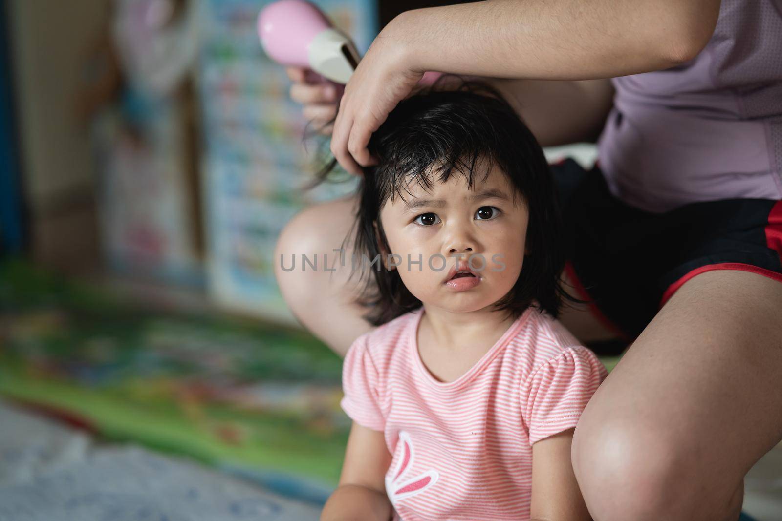 Mother and little girl drying hair with hairdryer after having bath by Wmpix