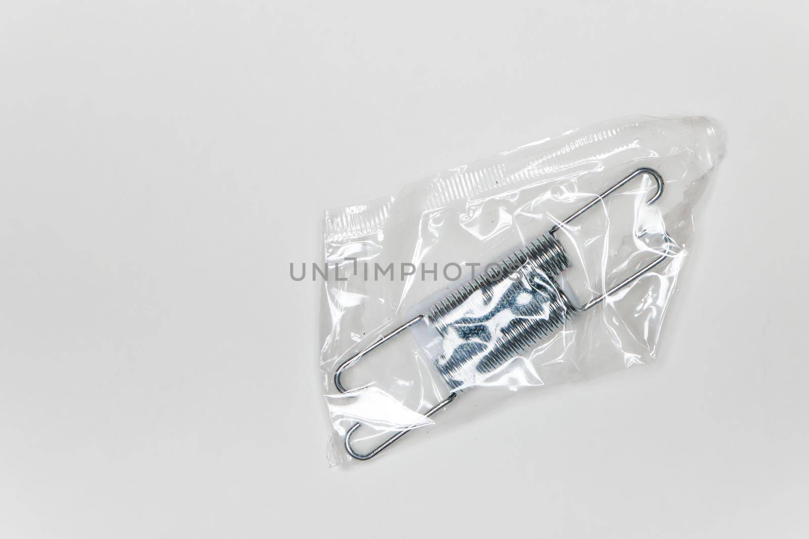 Two metal springs in a package, parts for car repair. A set of spare parts for servicing vehicle calipers. Details on white background, copy space available.