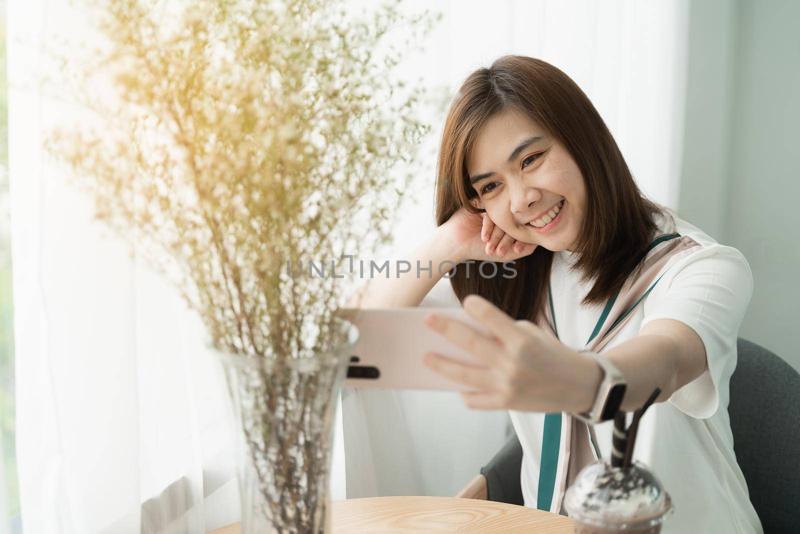 beautiful girl smiling using mobile phone selfie in the cafe, girl eat coffee and cake by Wmpix