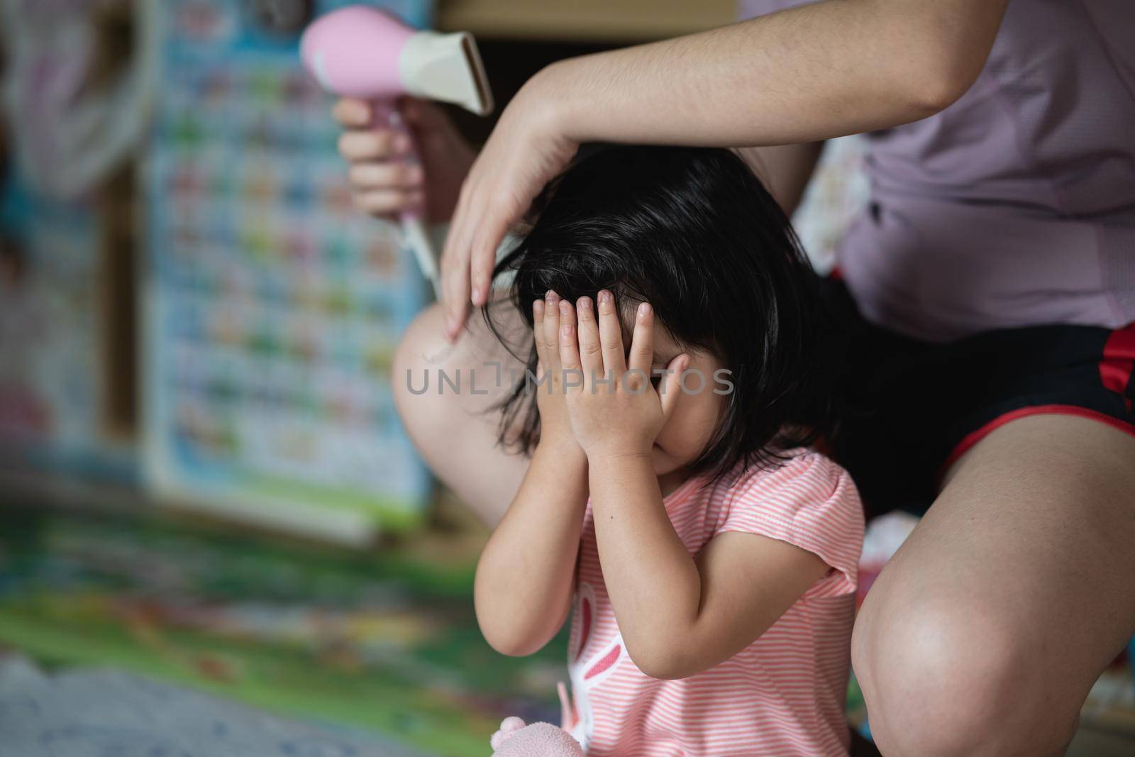 Mother and little girl drying hair with hairdryer after having bath