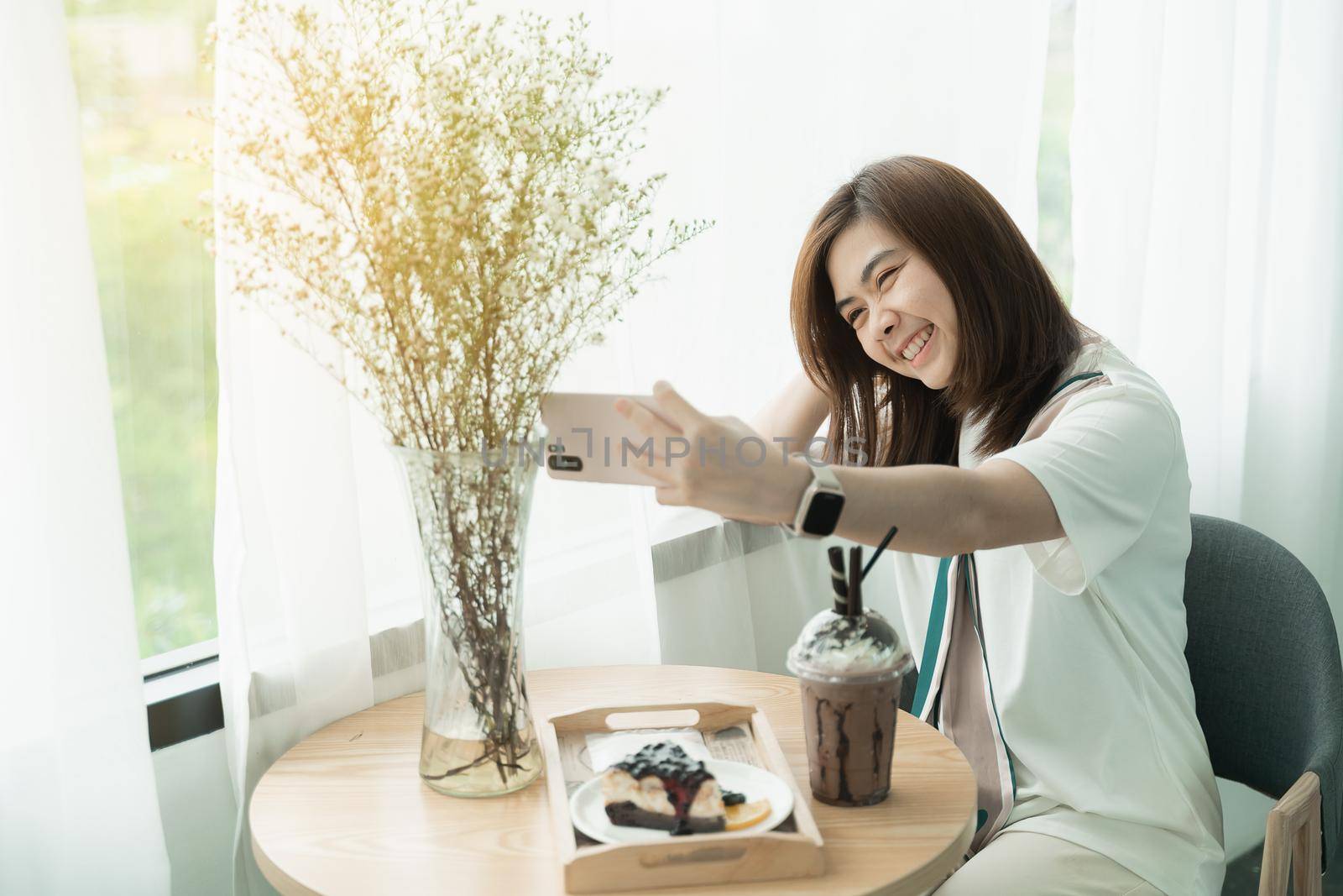 beautiful girl smiling using mobile phone selfie in the cafe, girl eat coffee and cake