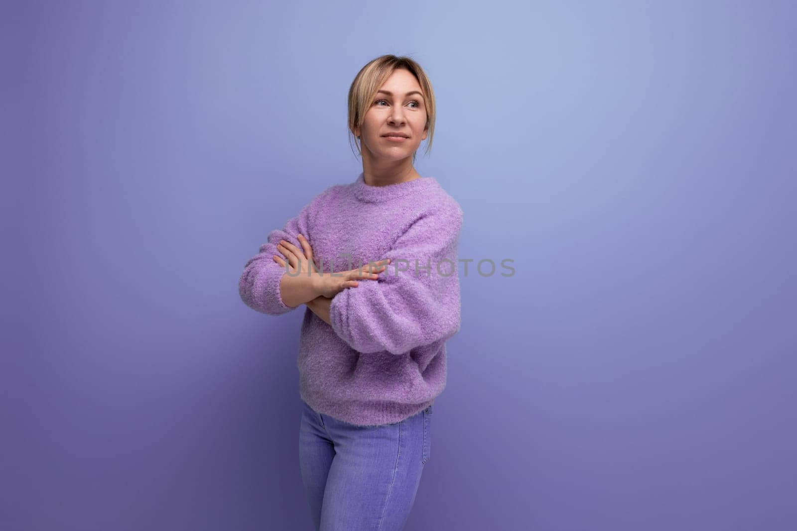 portrait of a charming cute blondie woman in a lavender sweater mysteriously looking away on a purple background with copy space by TRMK