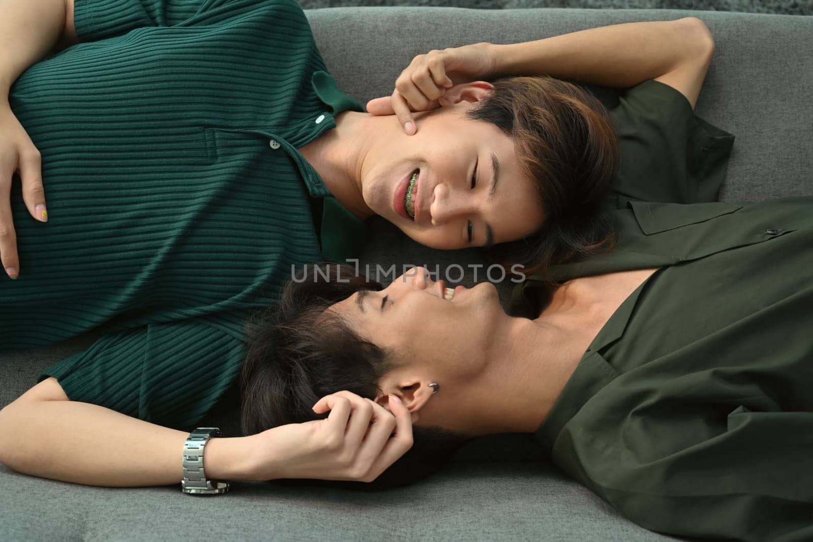 Young gay couple lying on comfortable sofa and looking into each other. LGBT, love and lifestyle relationship concept.