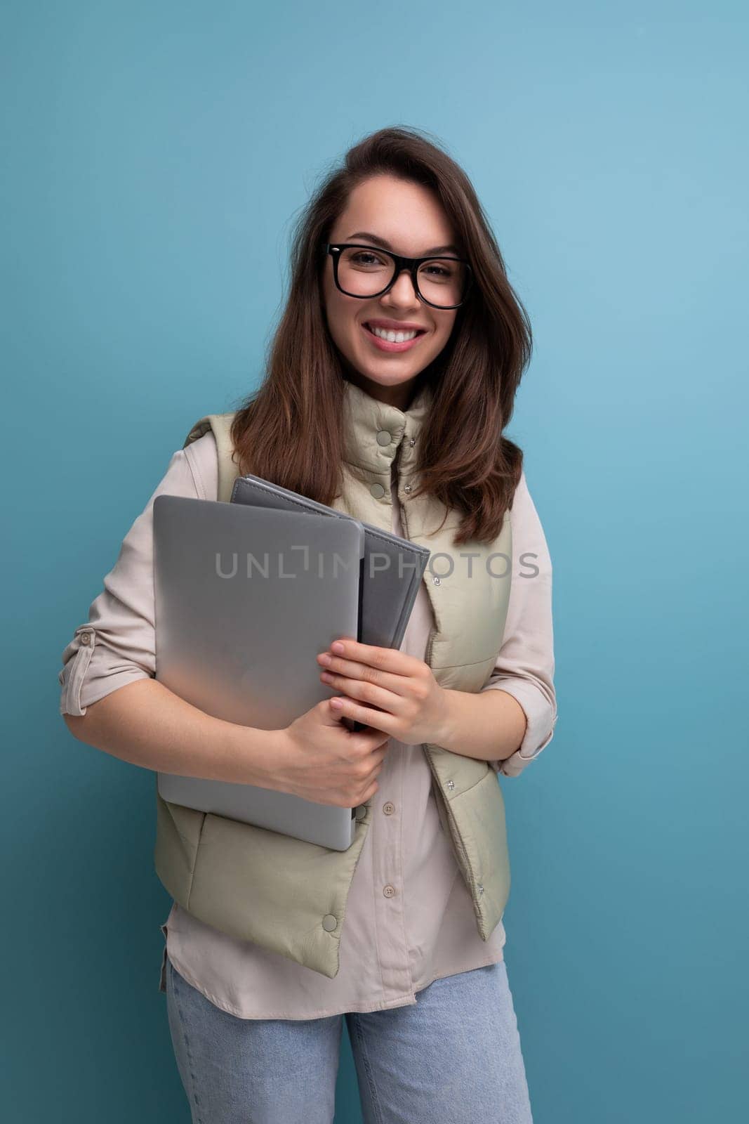 positive 30s lady student holding documents and laptop on empty space background.