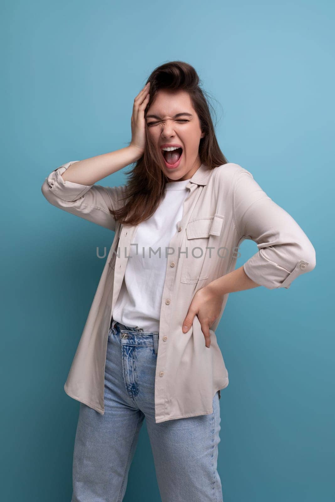 european young brunette female adult with chic well-groomed hair in a casual shirt on a blue background.