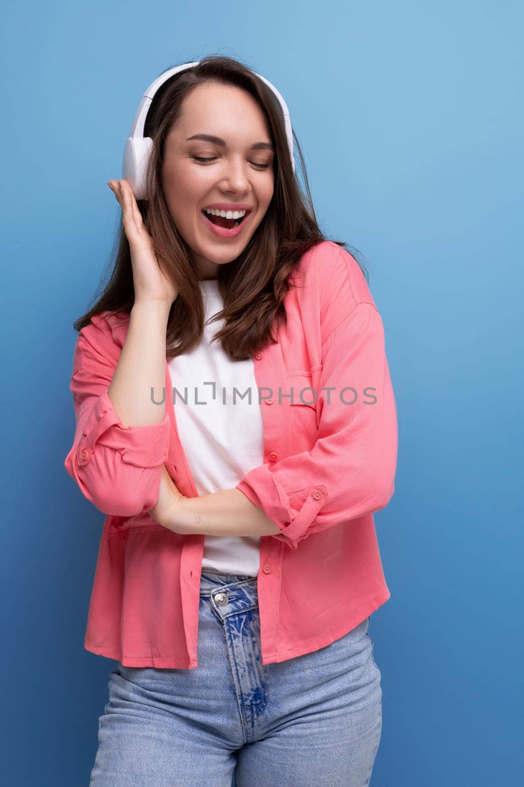 energetic brunette young woman in a shirt and jeans listens to her favorite music on headphones.