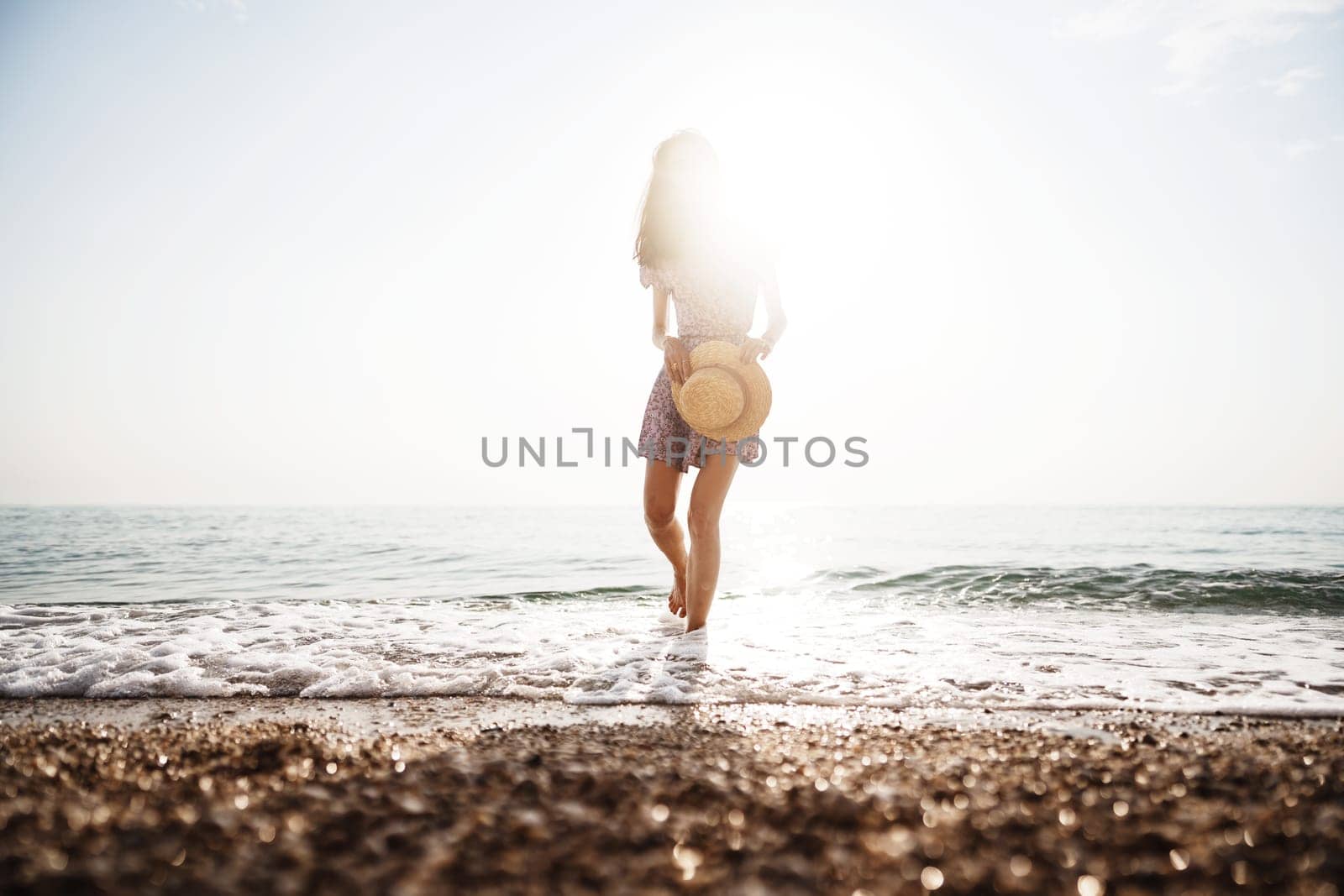 Lonely romantic young woman walks on the seashore at sunset