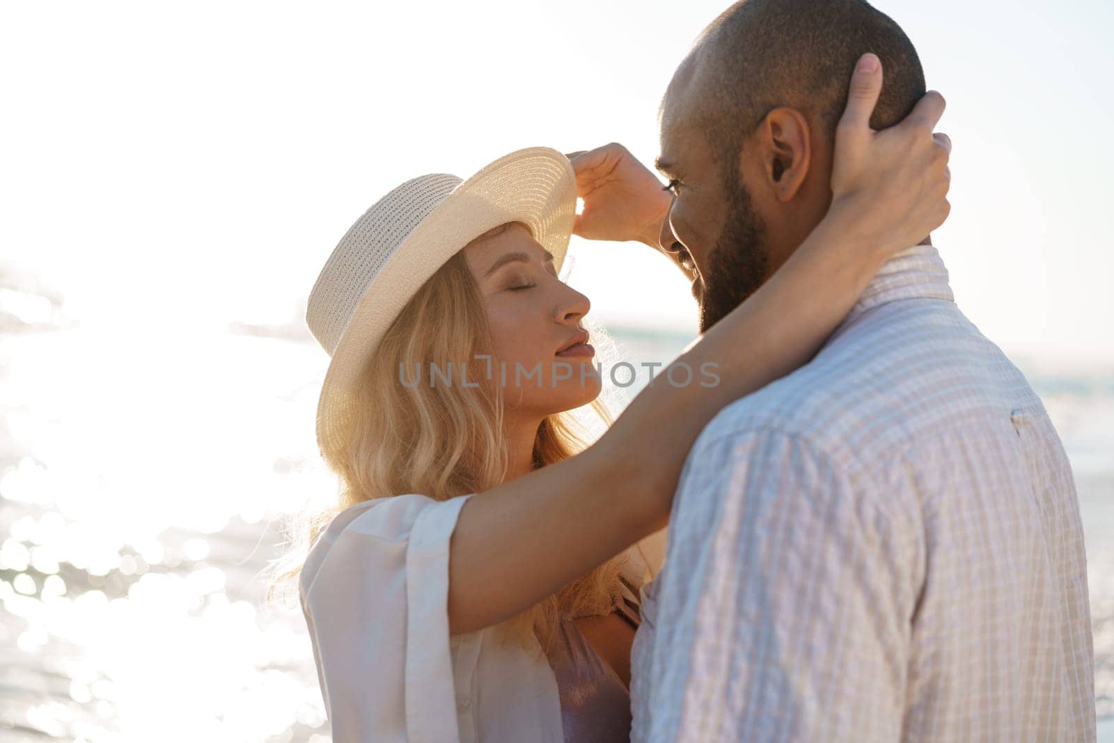 Beautiful young couple hugging on the beach by the water, close up