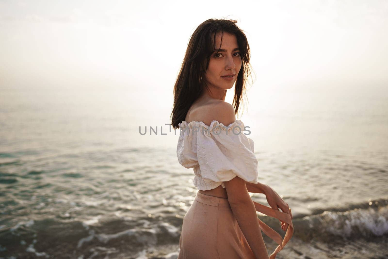 Lonely romantic young woman walks on the seashore at sunset