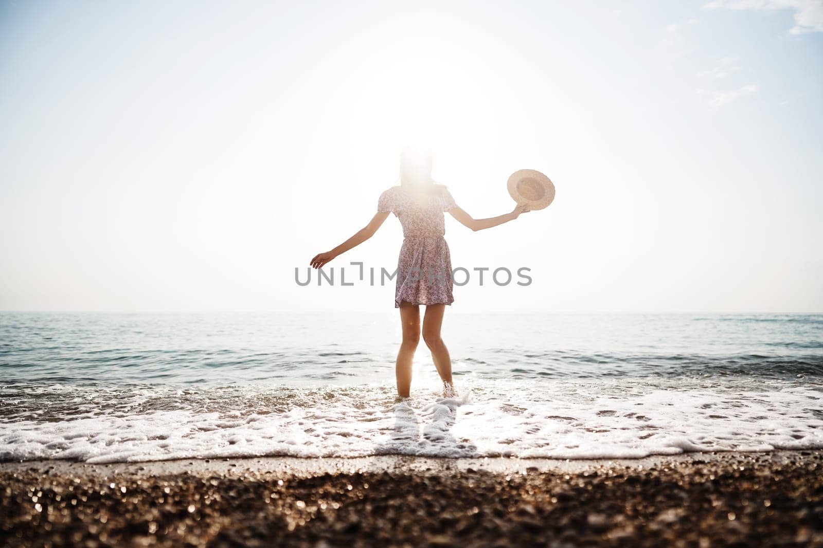 Lonely romantic young woman walks on the seashore at sunset