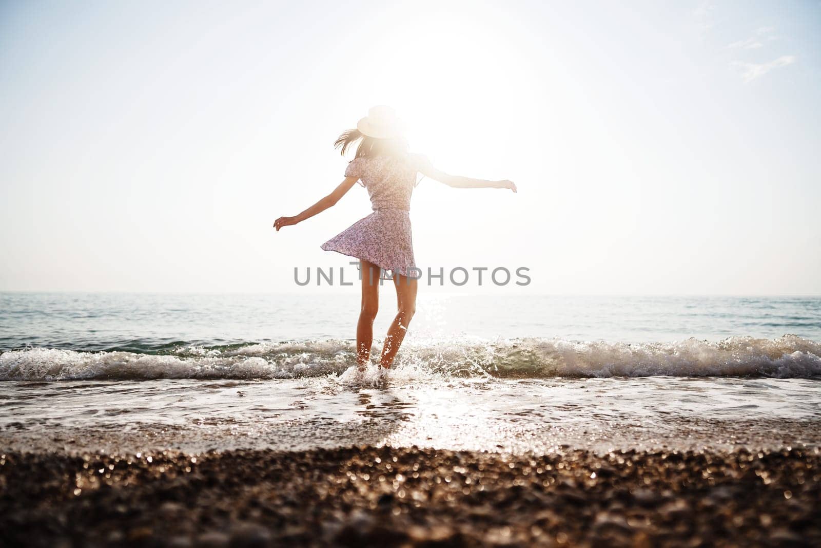 Lonely romantic young woman walks on the seashore at sunset