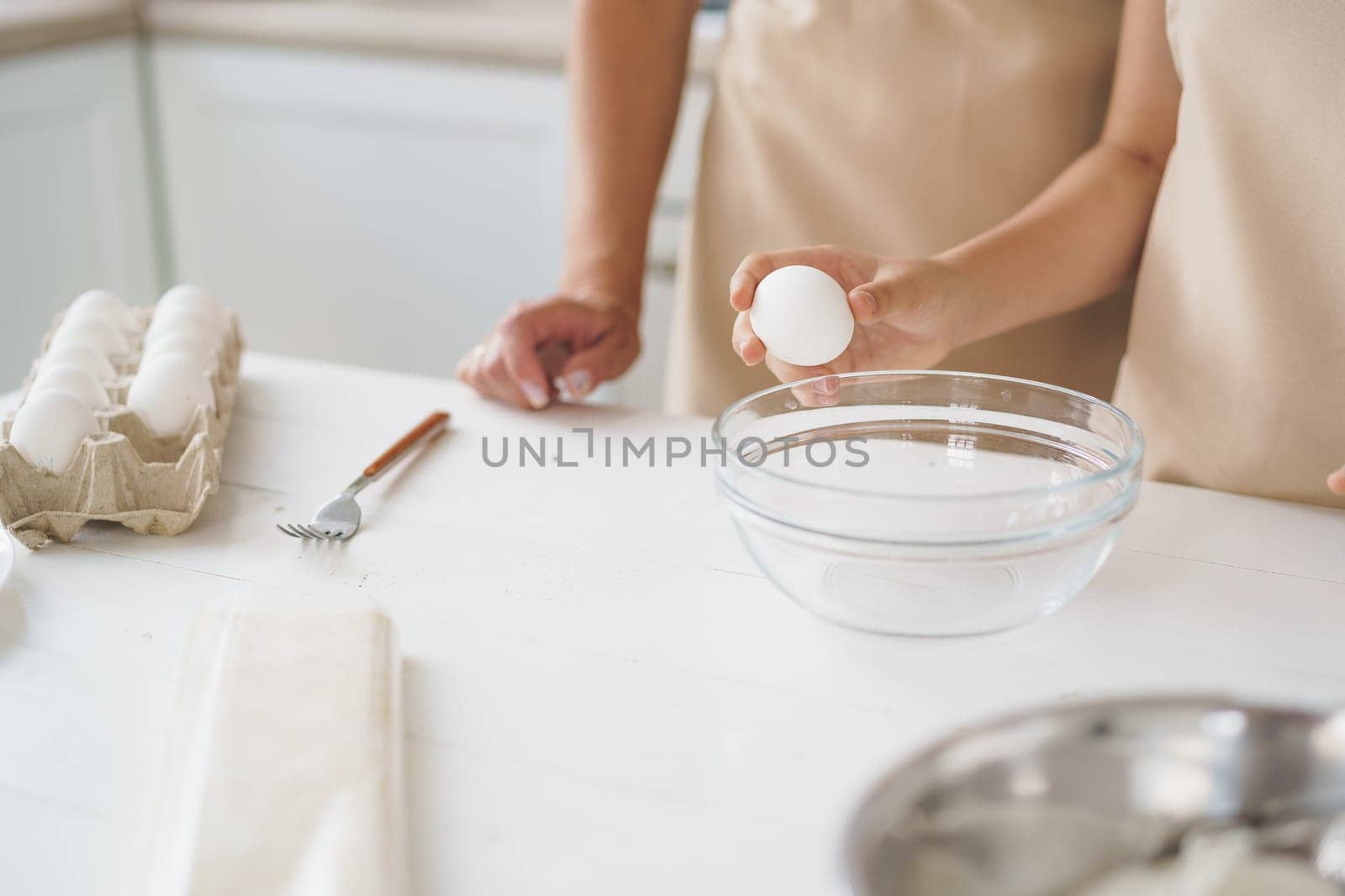 Close up of woman anf her daughter cooking dough in kitchen by Fabrikasimf