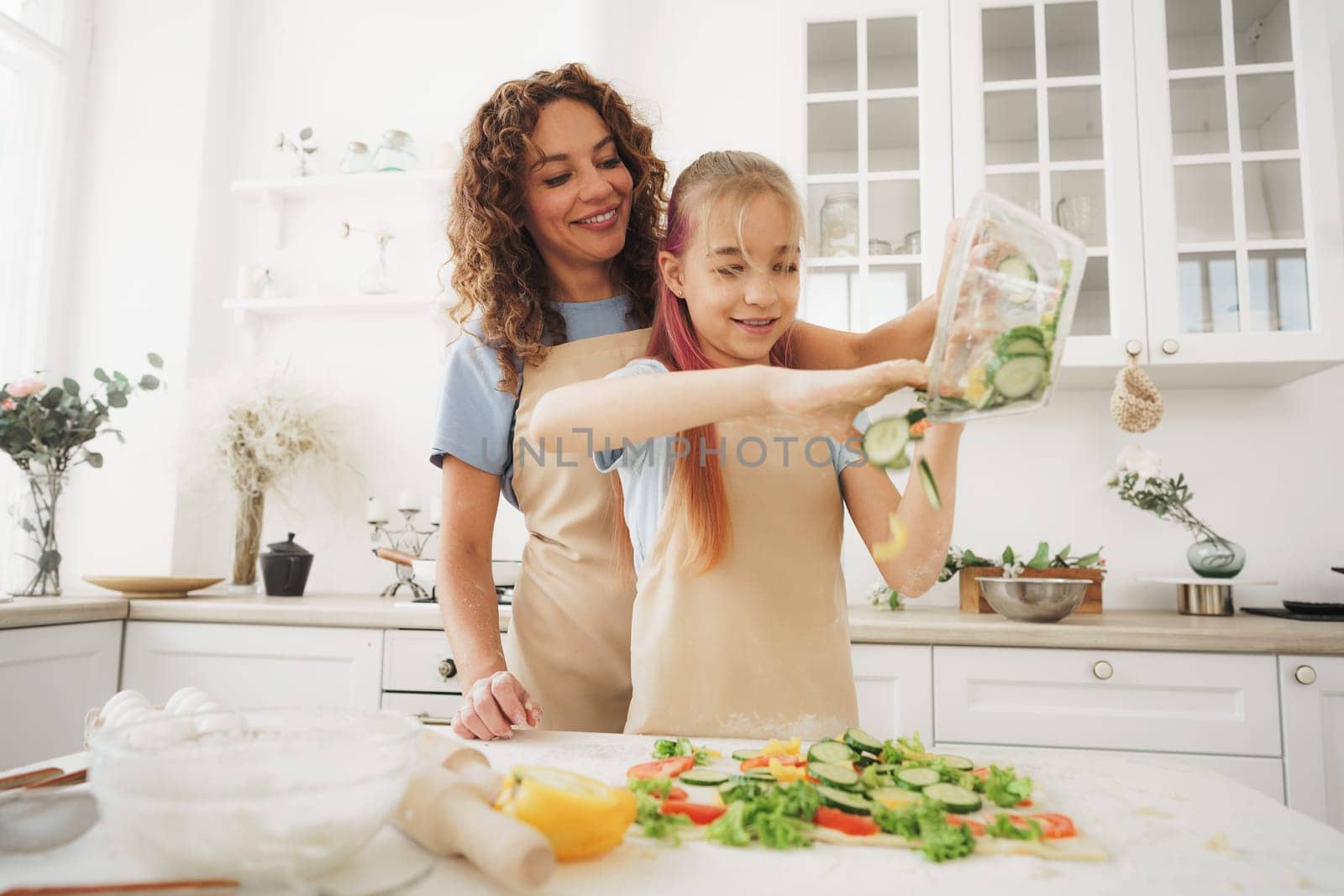 Close up of mother and daughter preparing vegan pizza in kitchen by Fabrikasimf