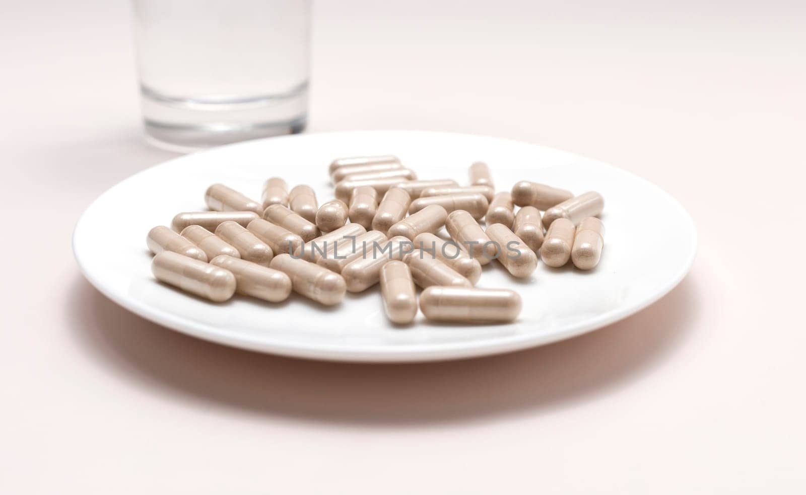 Closeup Handful Of Pills, Capsules OF Slippery Elm And Glass Of Water. Dietary Nutritional Supplement, Medication. Ulmus Fulva, Herbal Remedy Concept. Horizontal Plane, Horizontal plane.