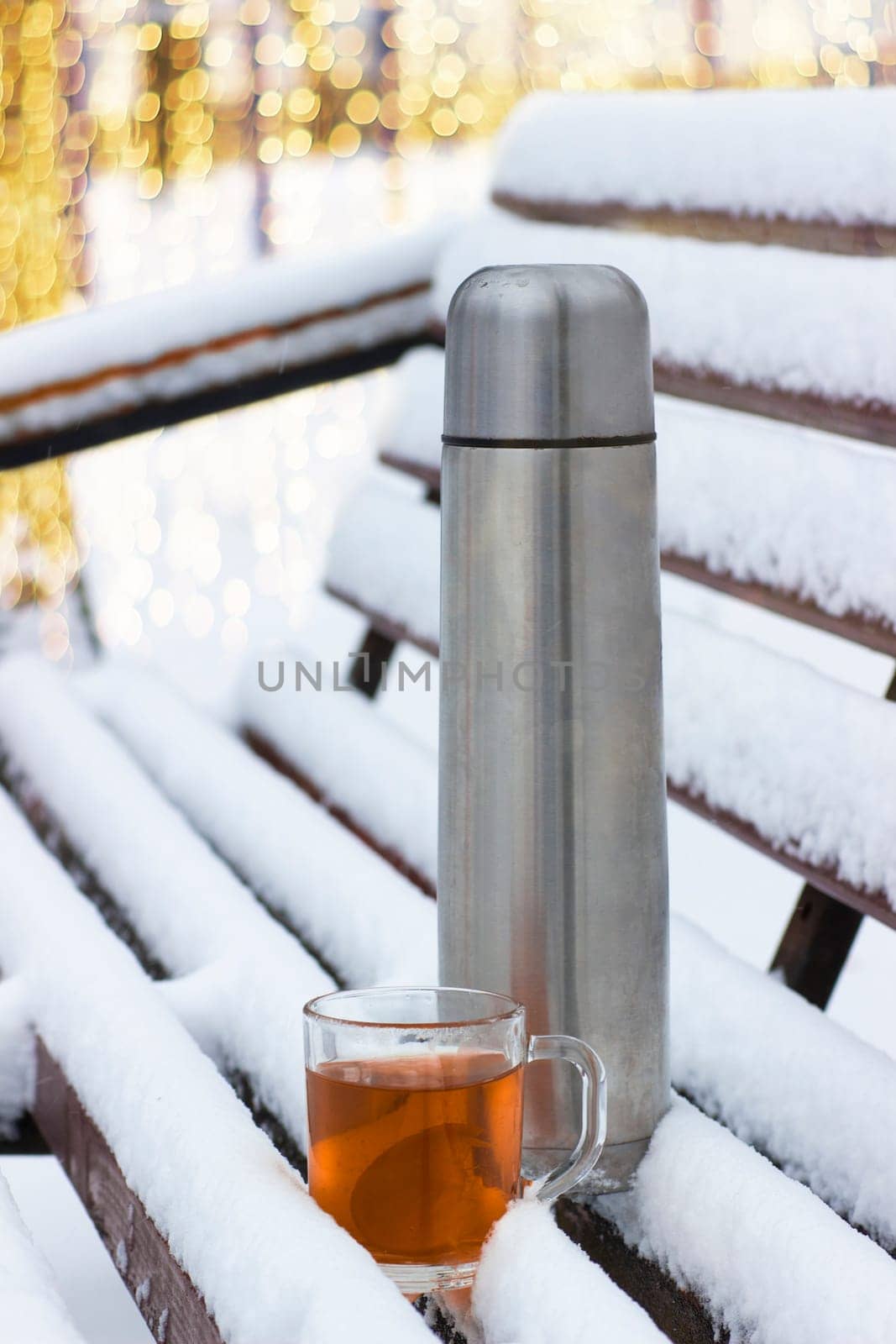 Cup with hot tea and thermos on a  snow background