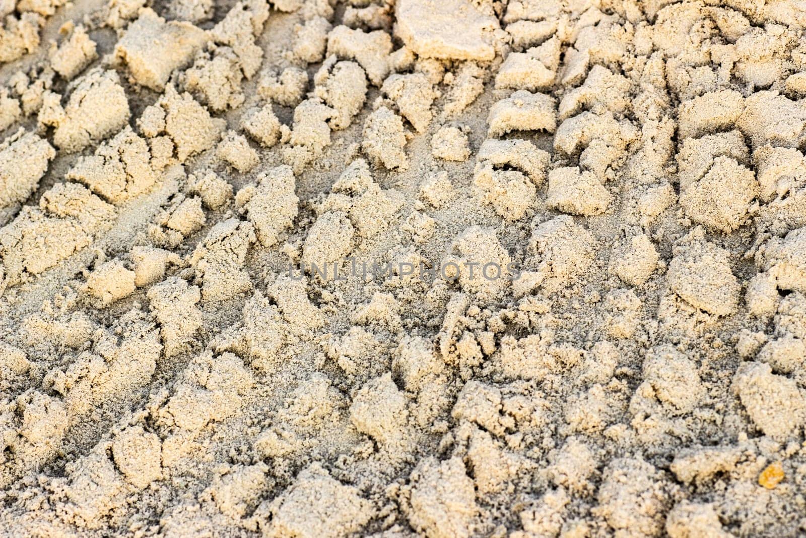 Trail from the tractor in the sand ground on the nature outdoors. Texture, background, sample