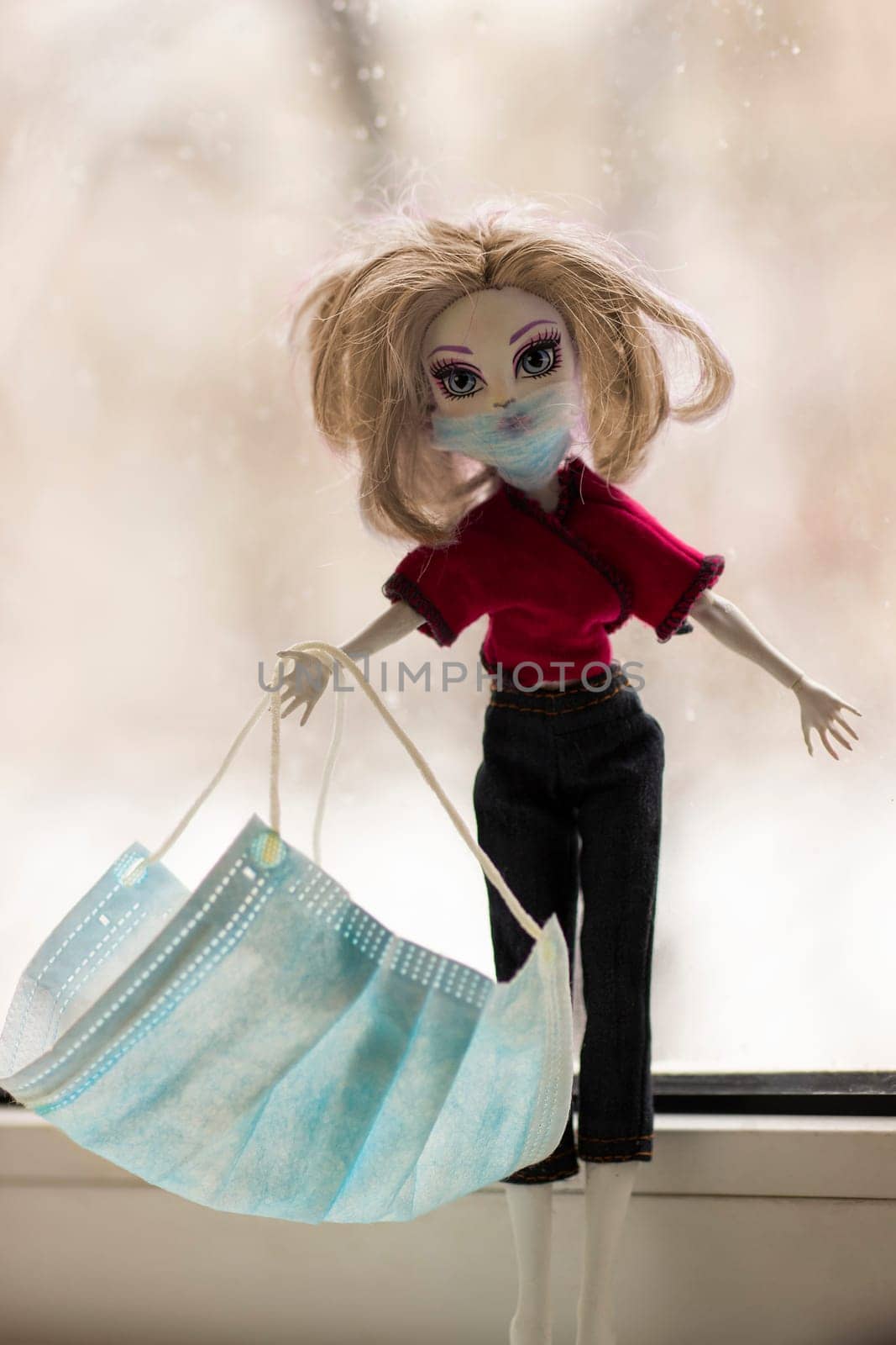 Child plaing during quarantine. Toy doll in protective 
facial mask 