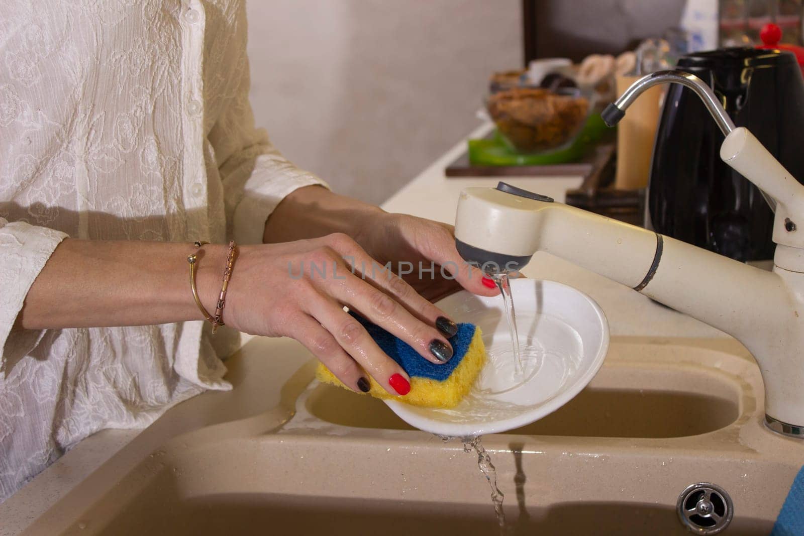 Young girl washing dishes on the kitchen, hands close up