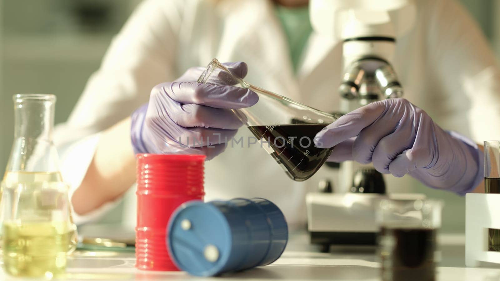 Scientist chemist holding in his hands flask with oil in chemical laboratory closeup. Quality control of composition of petroleum products concept