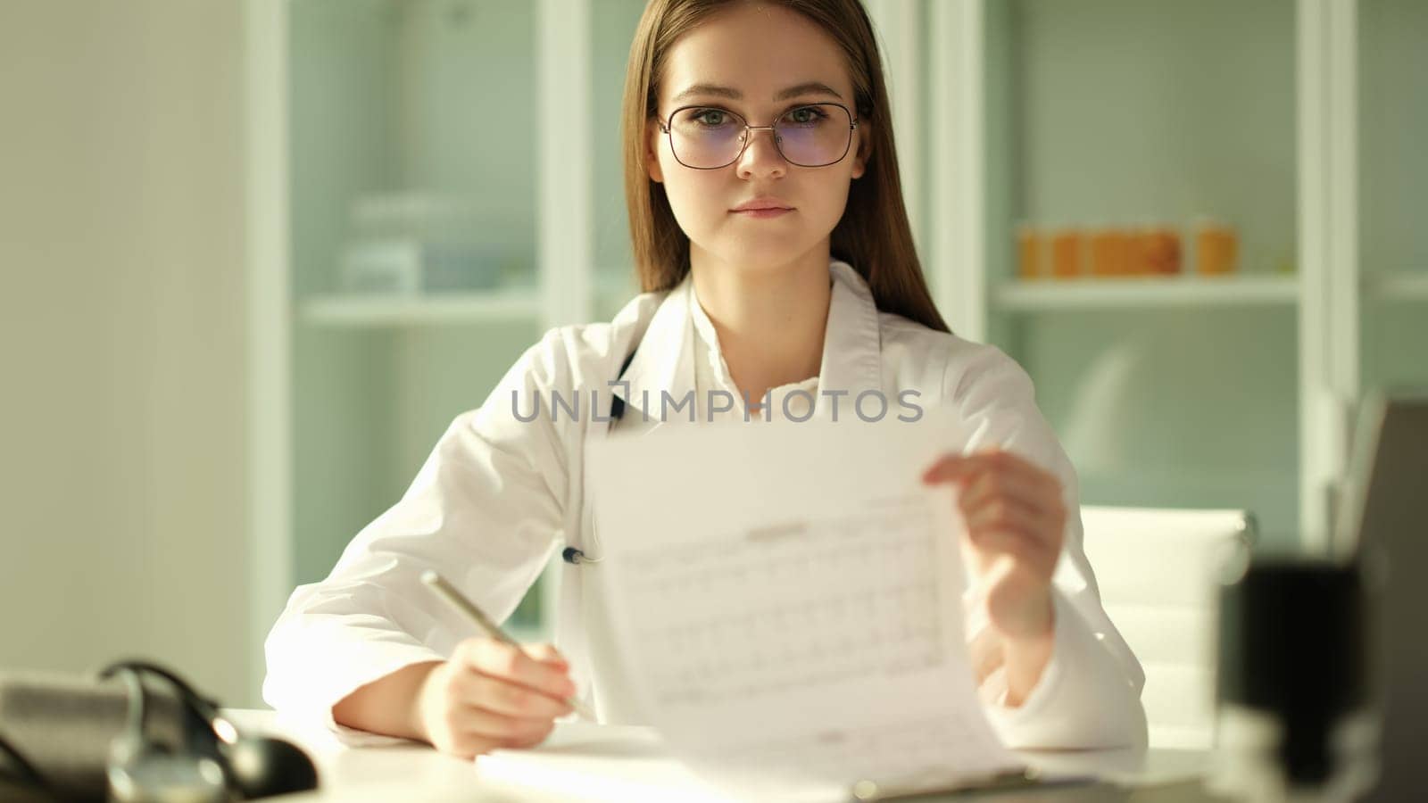 Doctor cardiologist examining patient cardiogram on paper in clinic. Diagnosis of heart disease concept