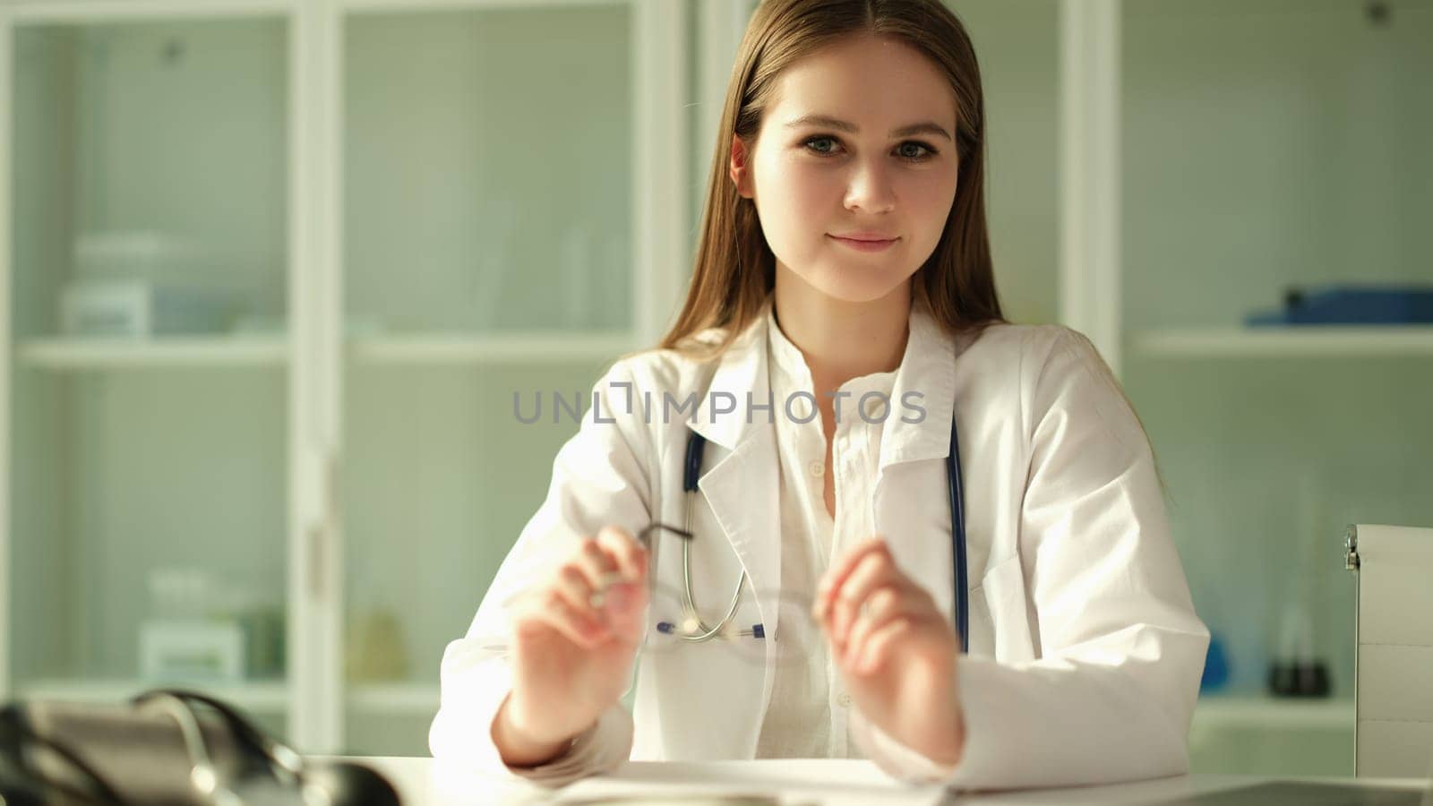Portrait of young woman doctor with glasses in her hands in clinic. Healthcare and medicine concert