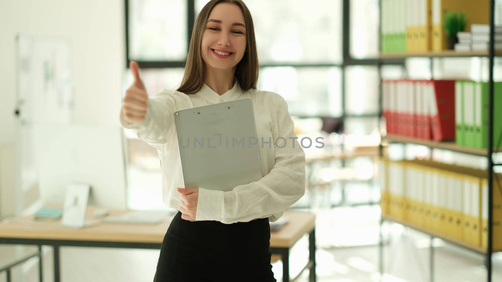 Smiling businesswoman showing ok thumb up in office. Successful career in business concept