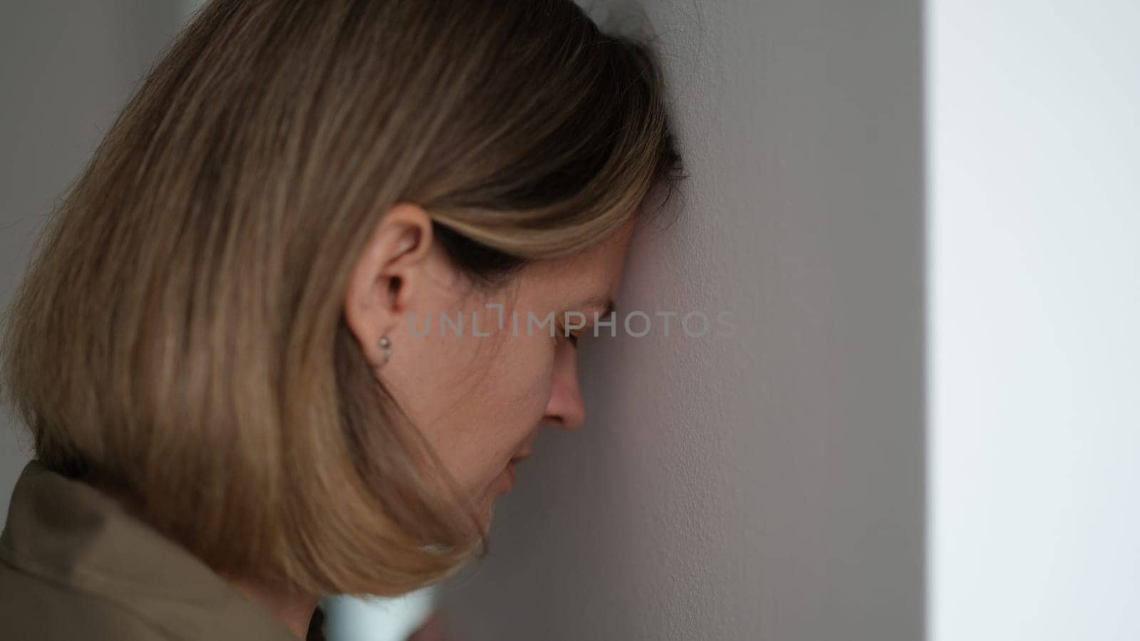 Tired depressed woman banging her head against wall. Hopeless situations concept