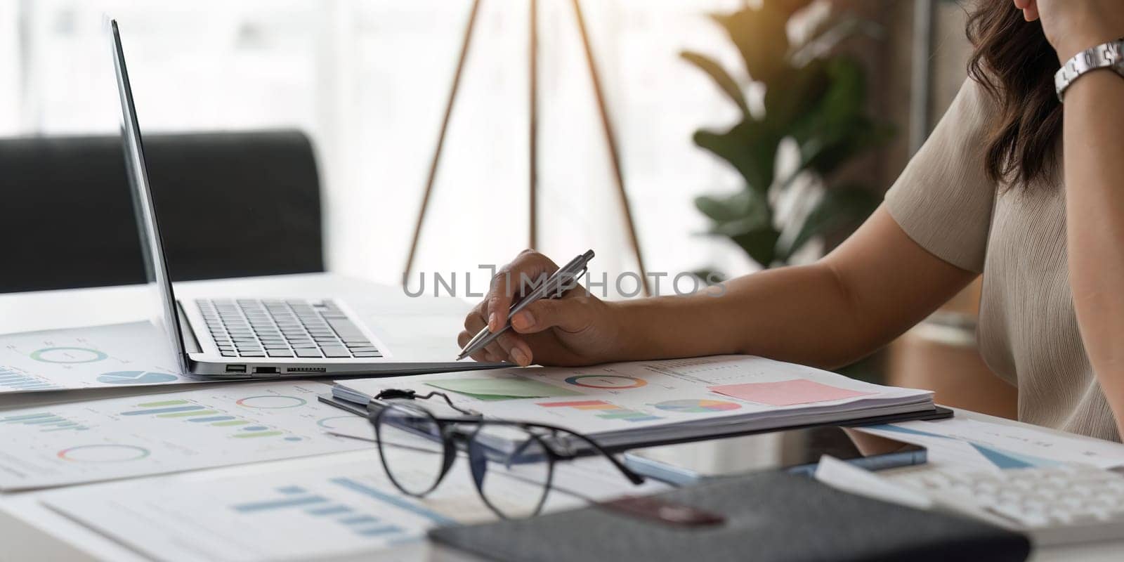 Closed up young business woman read write doing report figure paper chart, accountant calculating annual balance cash money report finance at office.