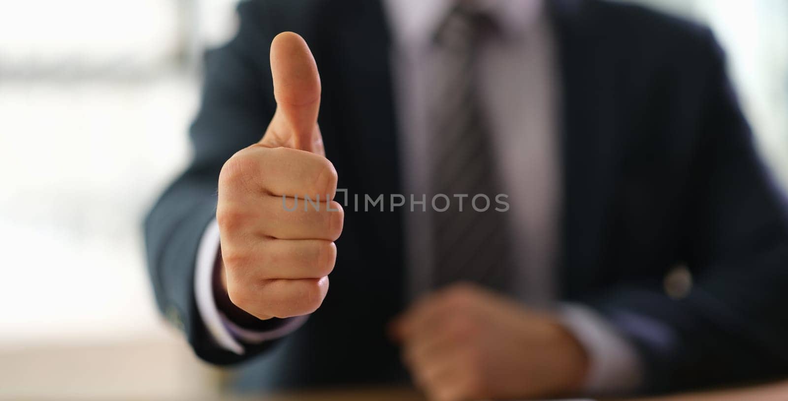 Businessman in suit showing thumbs up on successful deal closeup. Business success concept