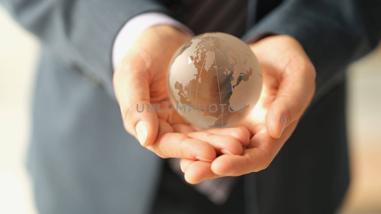 Hands of businessman in suit holding glass globe of earth closeup by kuprevich