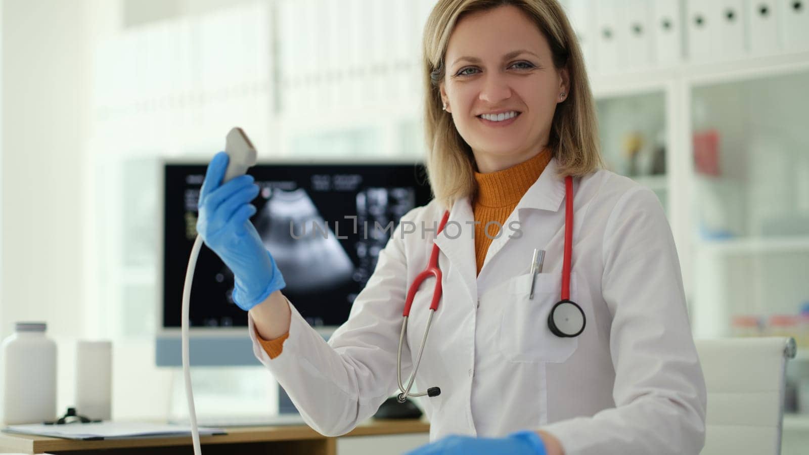 Smiling woman doctor holding ultrasound probe in hands to diagnose early pregnancy in clinic. Medical insurance concept