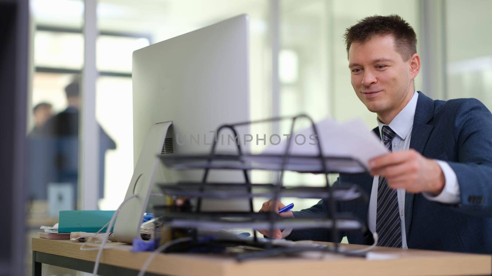 Businessman putting paper documents on stand on table in office. Business paperwork concept