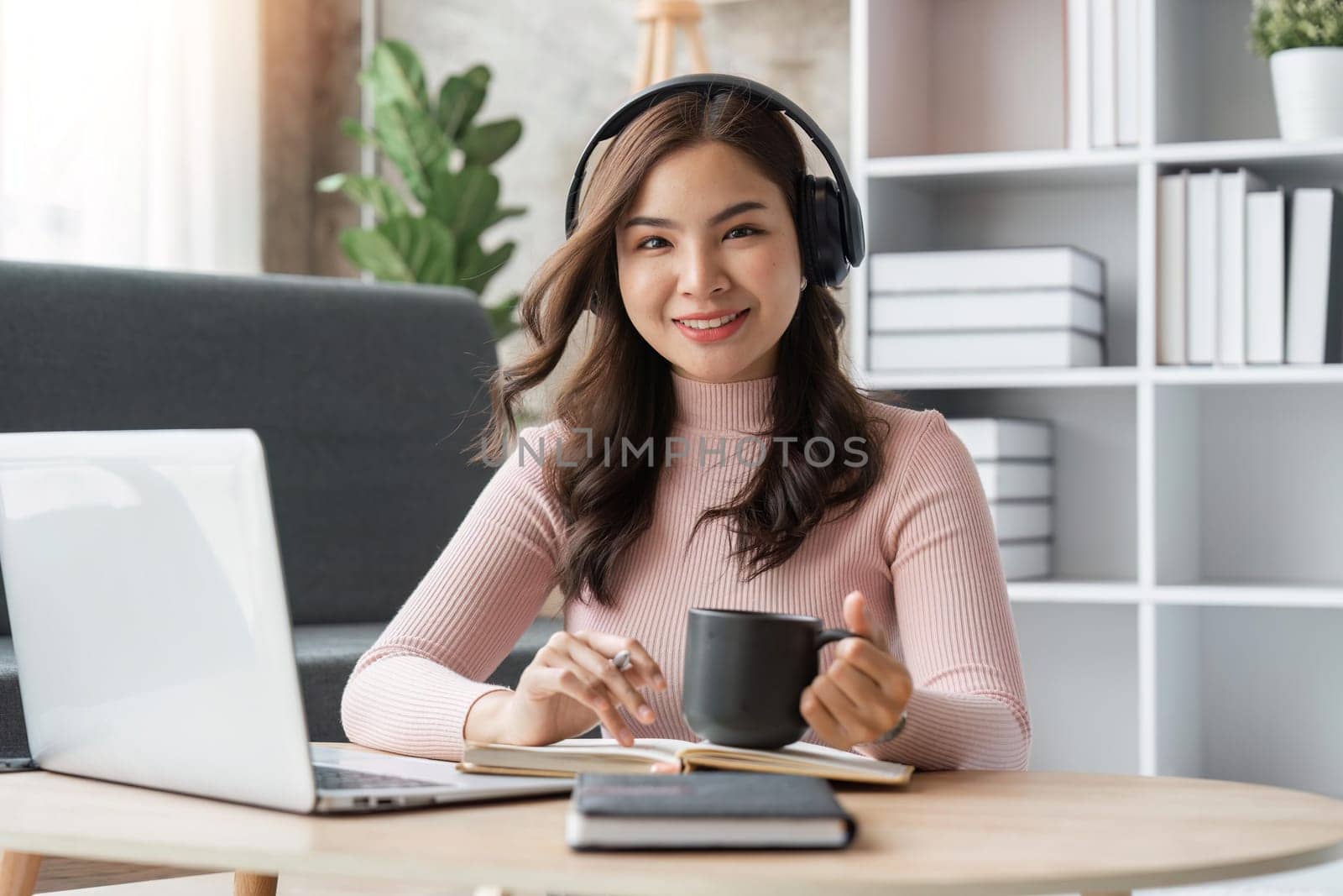 Beautiful asian woman relaxing using laptop computer while sitting on table with coffee, concept at home by nateemee