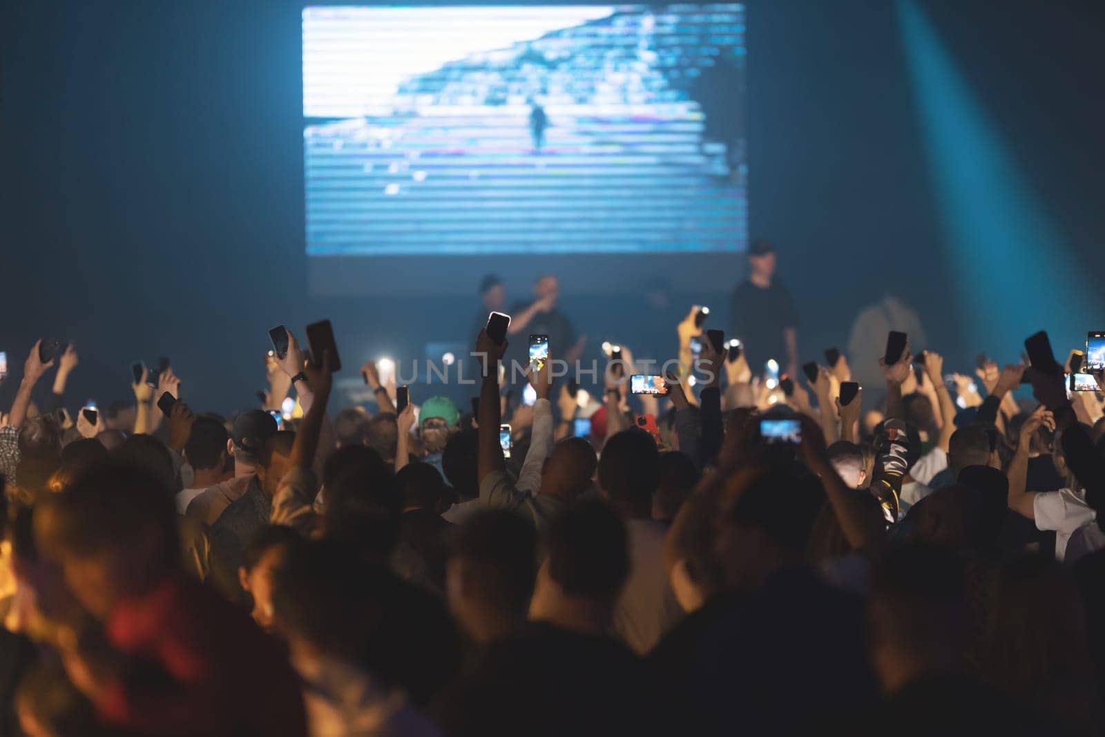 People shoot a concert on their phone cameras. Mid shot