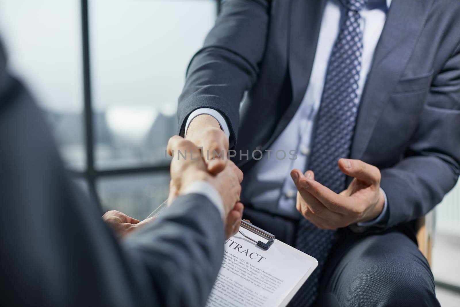 In the office, close-up of the hands of business businessmen while signing contracts and shaking hands to complete the deal.