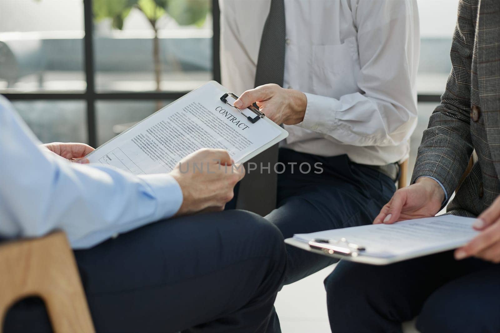 Close-up of businessmen looking at contract close-up while sitting in office