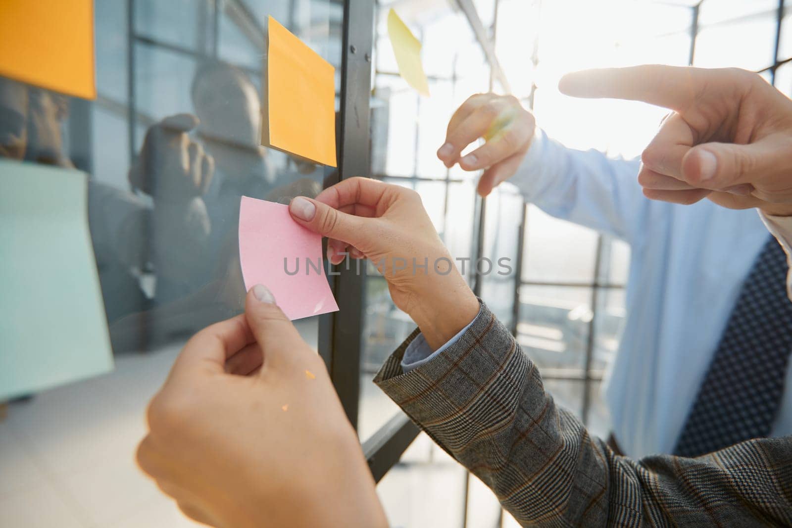 Many colorful note paper stickers with space for text pasted on glass wall.