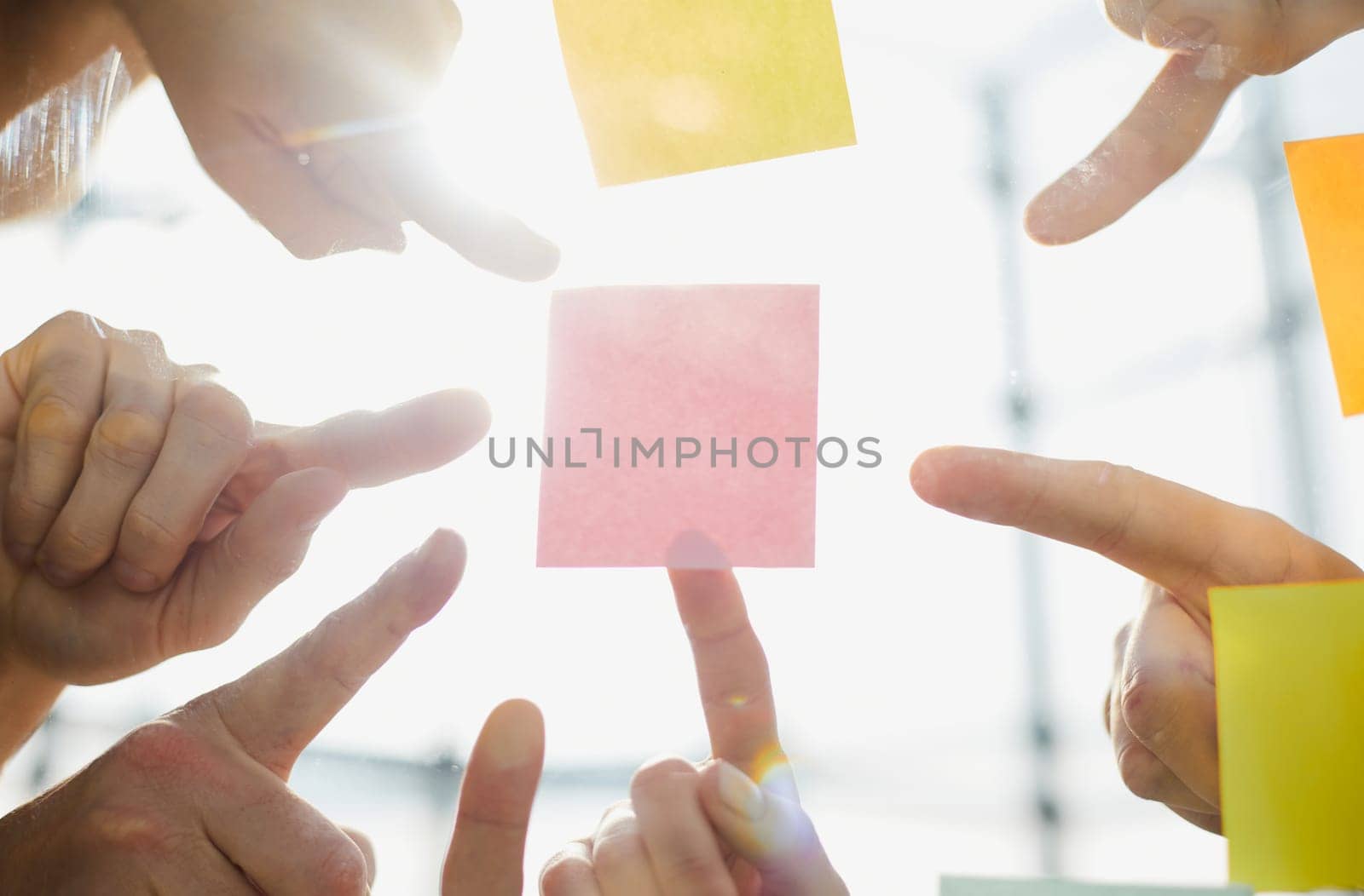 Hand pointing at pink paper or post against office background