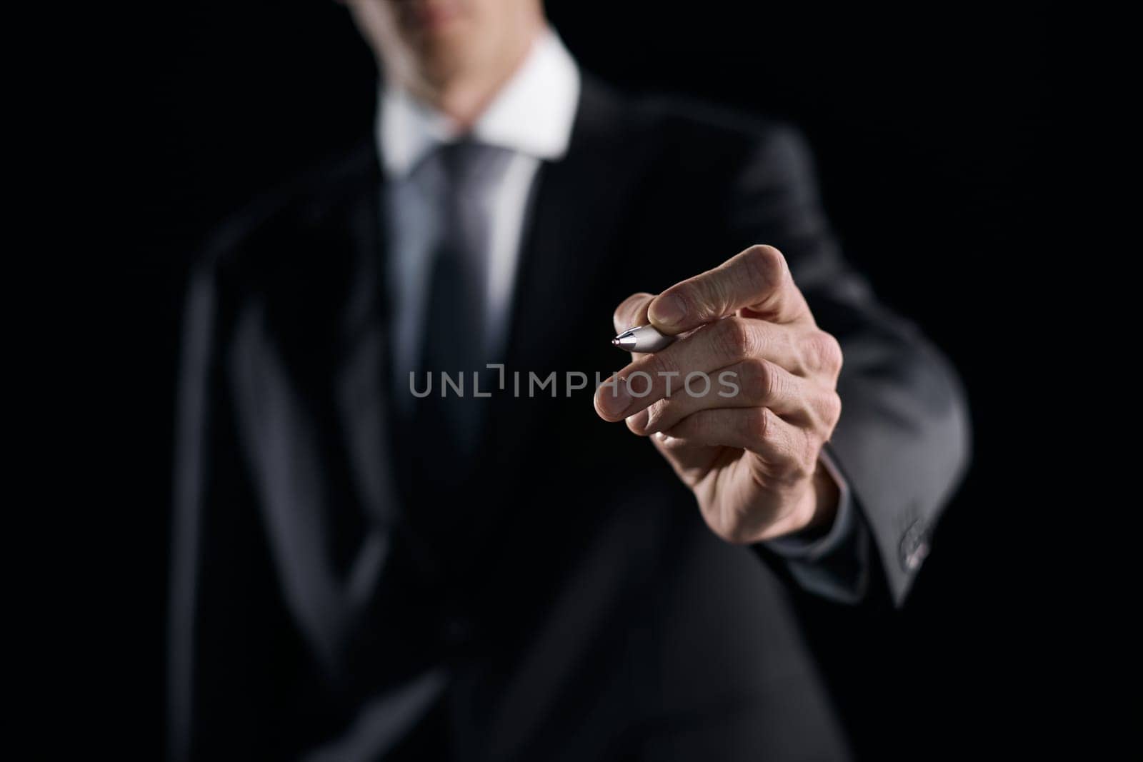 A hand holding a marker turned to the camera against a dark background