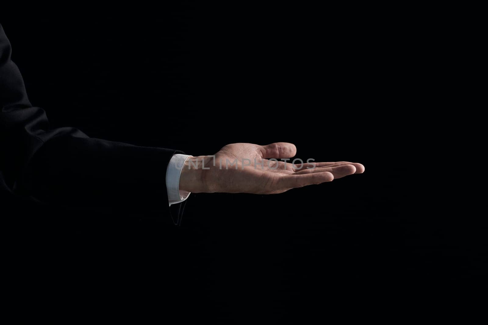 A man's hand is begging for something isolated on a black background. Palm up, close up.