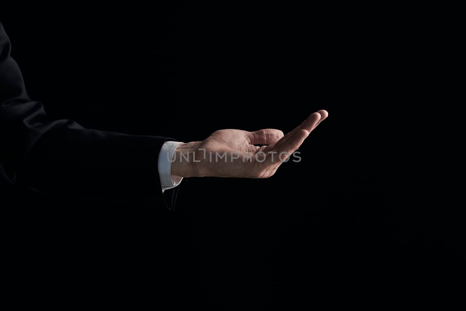 A man's hand is begging for something isolated on a black background. Palm up, close up.