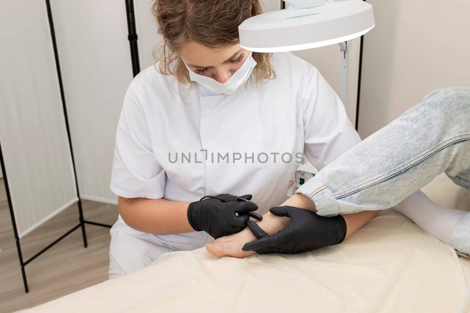 Trained Professional Remove Hair On Woman's Toes, Foot With Hair Removal Electrolysis Procedure. Electric Epilation In Beauty Salon. Horizontal Plane. Closeup Authentic High quality photo