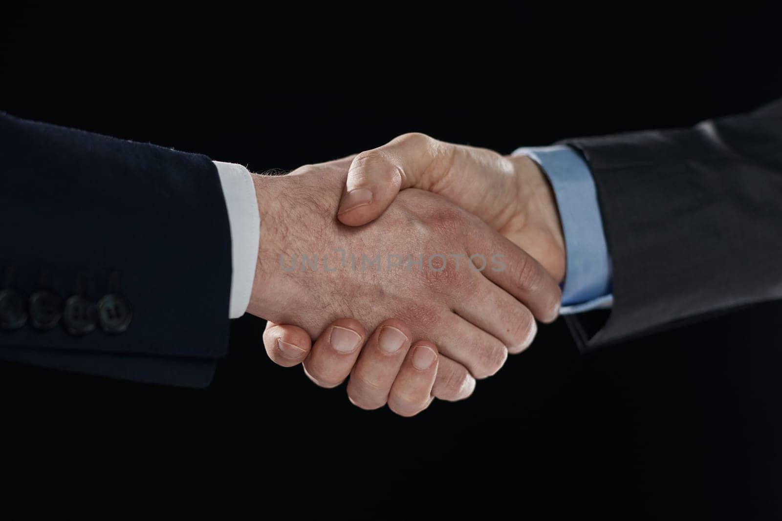 Confident businessman shaking hands on black background